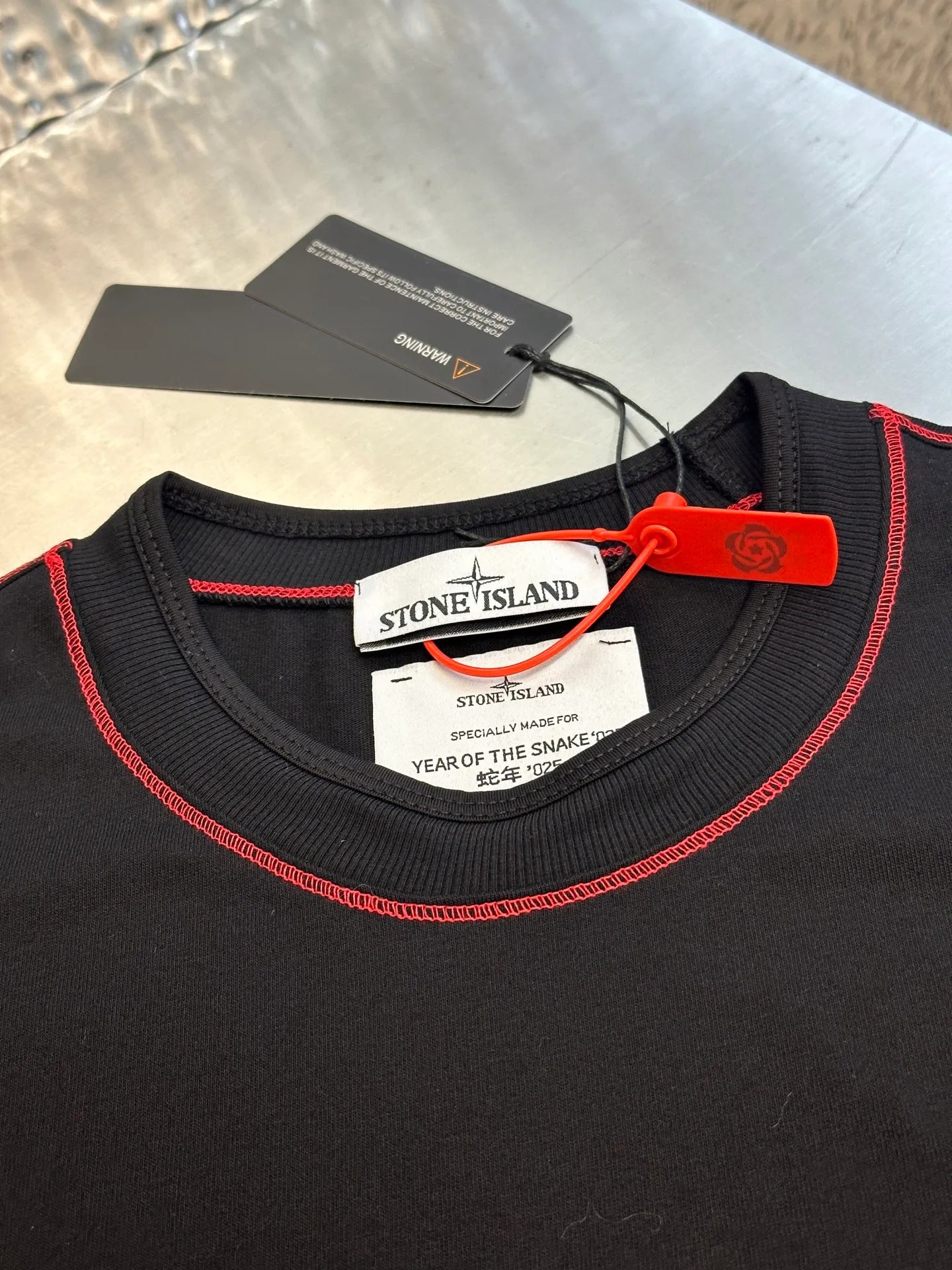 🅿️270 Stonelsland Badge Embroidered Short Sleeves Customized elegant black silk cotton and linen plain fabric, with iconic red Compass badge embroidery on the chest, stitching art, and the beauty of contrasting colors. The red stitches jump on the black base. The collision of fashion and creativity exudes irresistible charm. Imported machine embroidery technology is used, and advanced computer control systems and precision mechanical components are used to realize the red Compass badge embroidery operation. Special machine for reverse topstitching and fine sewing process. Special machine is used for topstitch sewing. It requires careful preparation of the reverse side of the garment before sewing to ensure that the sewing lines are straight, the stitches are even, and the edges are smooth and beautiful.  size：s m l xl